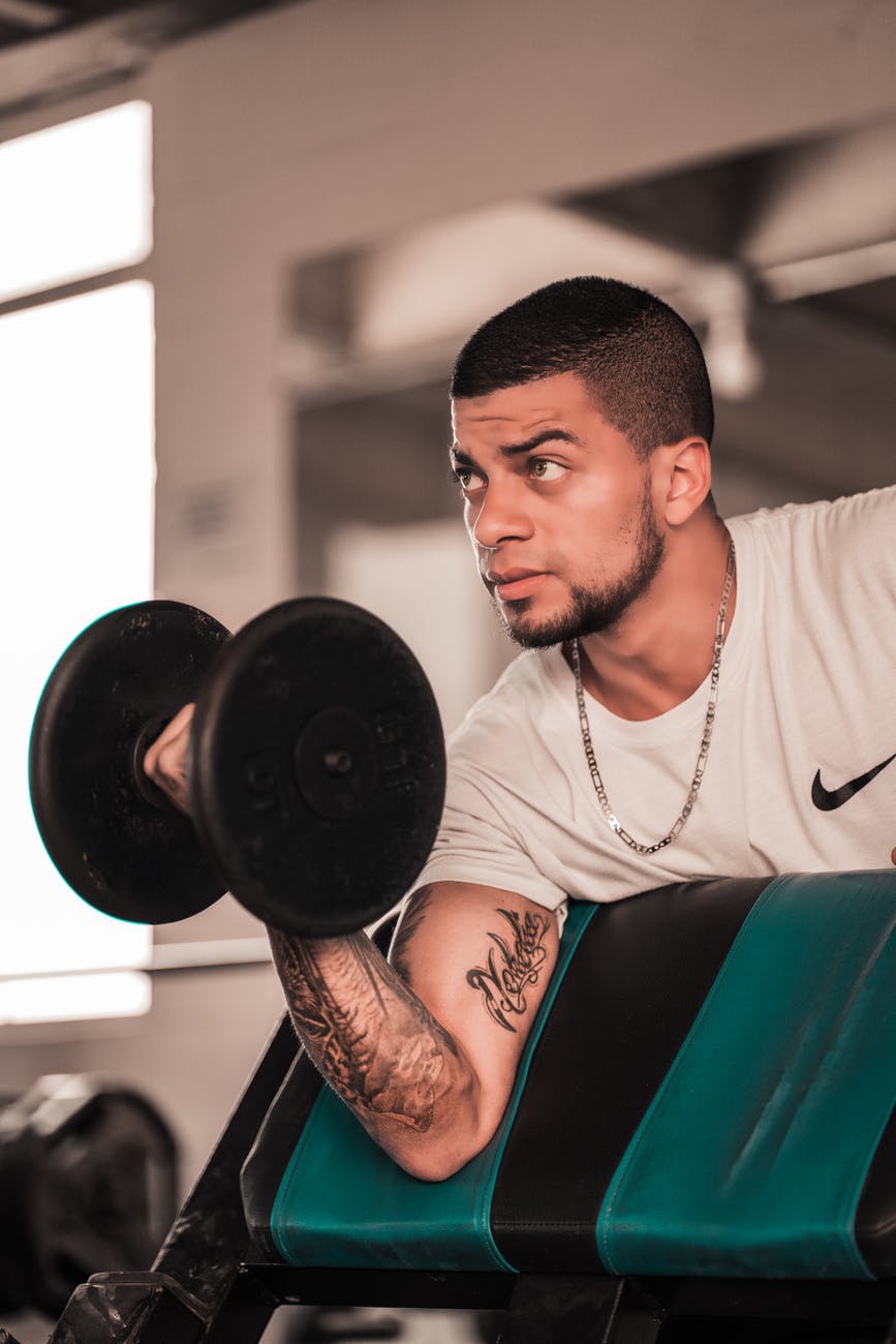 man in white crew neck t shirt holding black dumbbell